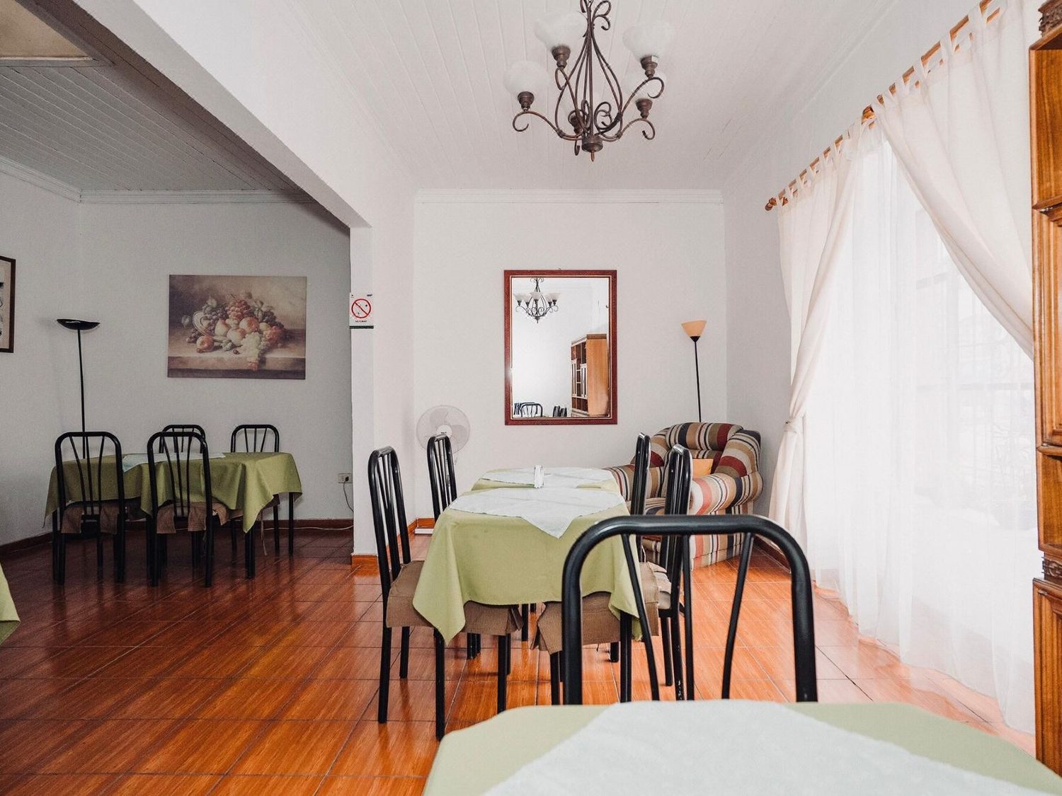 Comedor del hotel con mesas vestidas, lámpara de araña y piso de madera