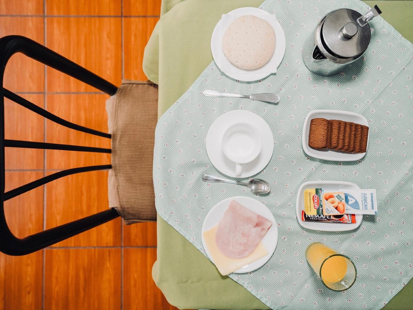 Desayuno servido: café, pan, mermelada, jugo y fruta sobre la mesa del comedor