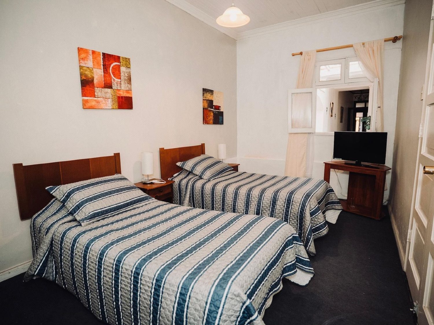 Habitación doble del hotel con dos camas individuales, cubrecamas a rayas y televisor