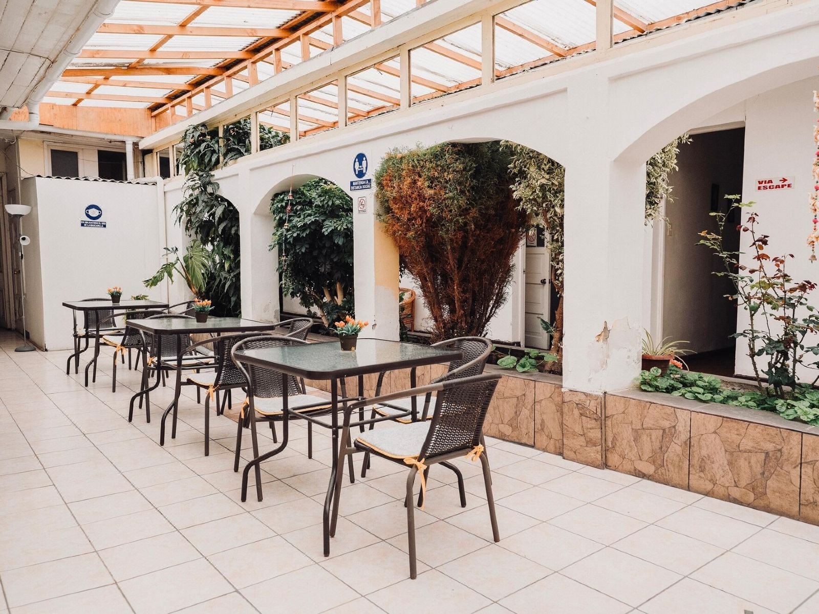 Patio del hotel con arcos encalados, enredaderas y mesas puestas para el desayuno